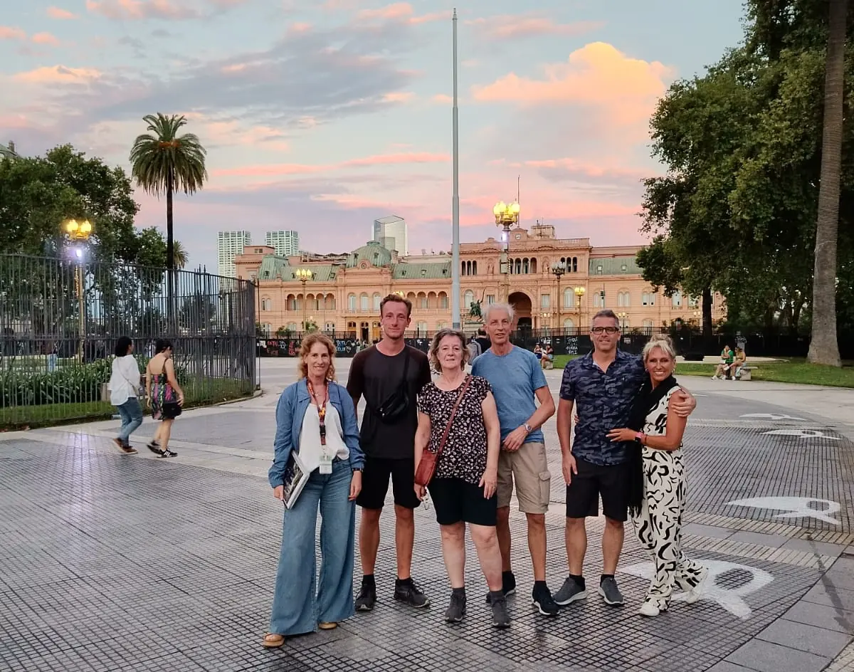 Débora with a small group at Plaza de Mayo, with the Casa Rosada behind them at sunset